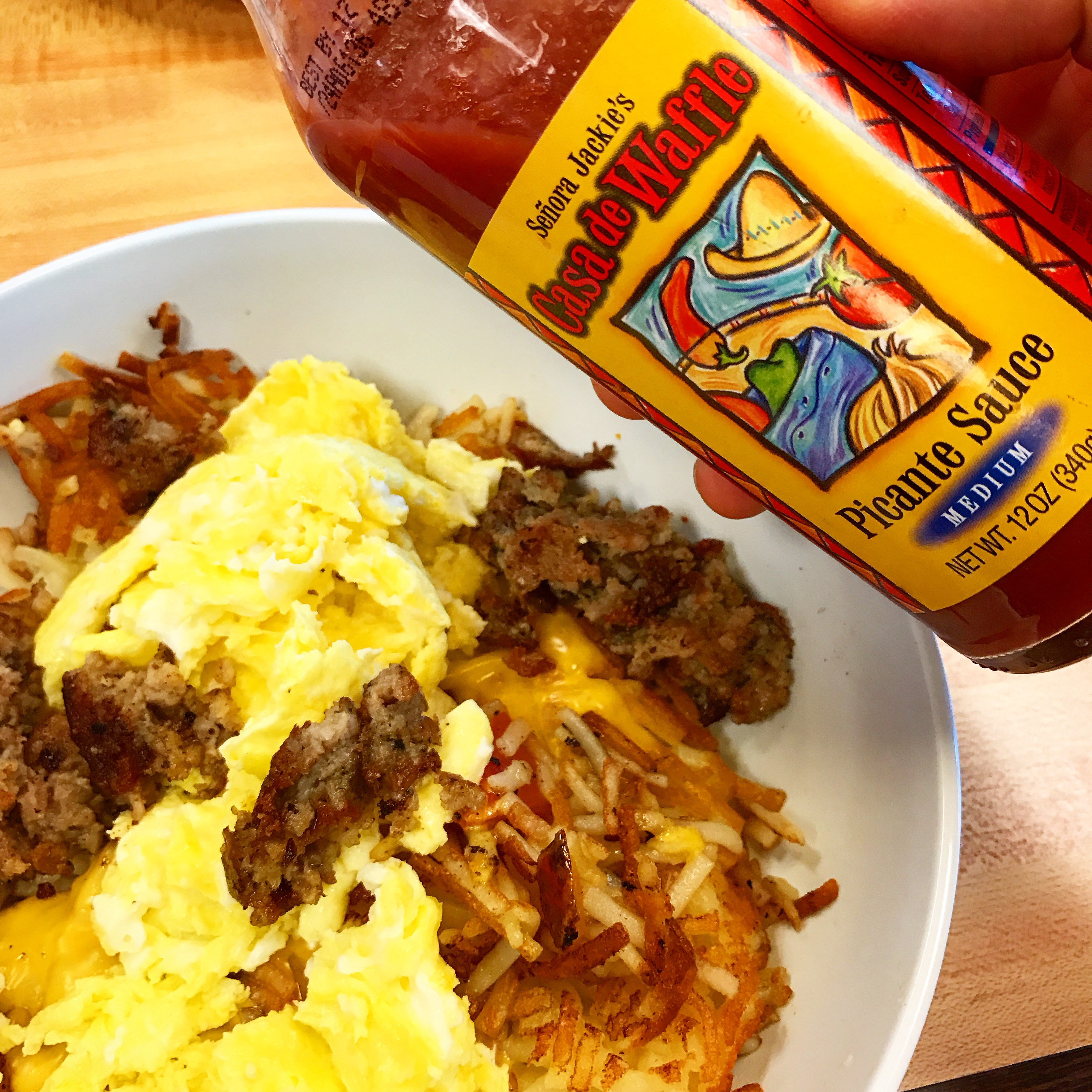 A hash-brown in a bowl with eggs andf ground patty on top.