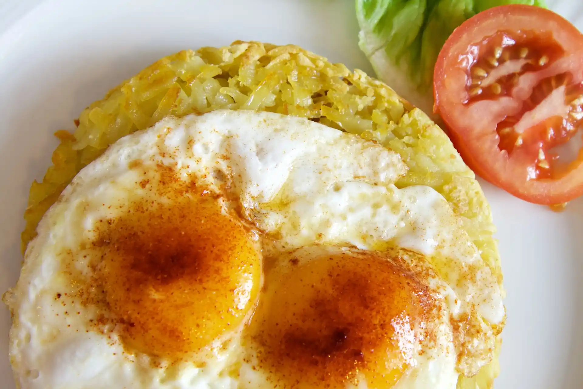 A hashbrown patty topped with two sunny-sideup egg.